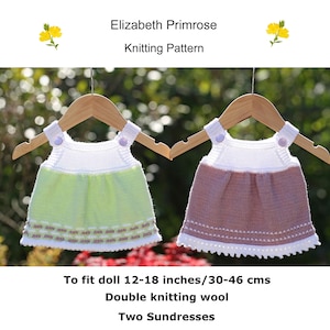 May include: Two knitted doll sundresses hanging on wooden hangers. The sundresses are white with a green and a brown skirt. The text on the image reads "Elizabeth Primrose Knitting Pattern" and "To fit doll 12-18 inches/30-46 cms Double knitting wool Two Sundresses".