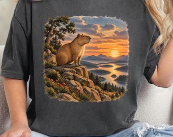 Camiseta divertida con estampado de capibara al atardecer en un lago de montaña, naturaleza y vida silvestre.
