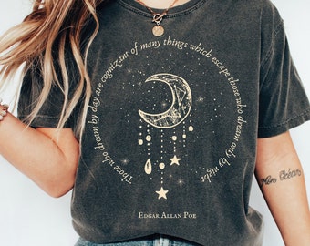 May include: A dark gray t-shirt with a crescent moon graphic and a quote by Edgar Allan Poe: "Those who dream by day are cognizant of many things which escape those who dream only by night."