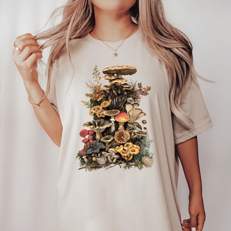 May include: A white t-shirt with a vintage illustration of a variety of mushrooms in shades of brown, red, yellow, and green.