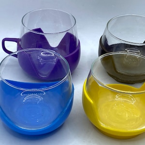 May include: Four glass cups with colorful silicone sleeves. The cups are clear glass and the sleeves are purple, brown, blue, and yellow.