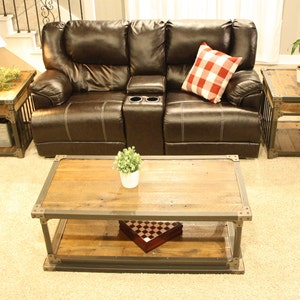 May include: A brown leather sofa with a red and white checkered pillow, a wooden coffee table with a metal frame, and two matching wooden end tables with metal frames. The coffee table has a game board on the lower shelf.