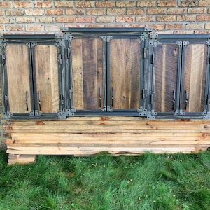 May include: Three rustic wooden cabinet doors with black metal frames and hinges. The doors are made of reclaimed wood with a natural finish. The cabinet doors are mounted on a wooden base.