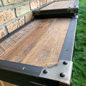 May include: A wooden cabinet with a black metal frame and metal corner brackets. The cabinet has a rustic wood finish and is made of reclaimed wood.