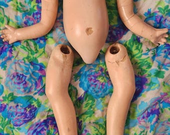 May include: Disassembled vintage doll parts, including the torso, two arms, and two legs. The doll parts are made of a pale pink plastic and are in fair condition.