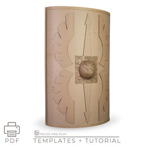 Könnte beinhalten: Eine hellbraune, gebogene Schildvorlage mit geätzten Designs, darunter eine zentrale Kugel und ein Pfeil. Das Schild hat eine strukturierte Oberfläche und ist mit "REUSE AND PLAY TEMPLATES + TUTORIAL" und einem PDF-Symbol beschriftet.