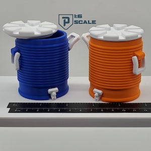 May include: Two miniature plastic water coolers, one blue and one orange, with white lids and spouts. The coolers are on a white surface with a black ruler.