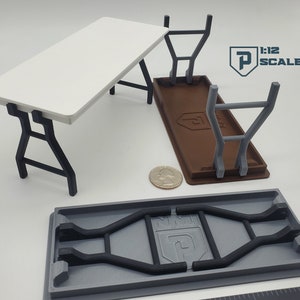 K&ouml;nnte beinhalten: Ein wei&szlig;er Klapptisch mit schwarzen Metallbeinen. Der Tisch ist im Ma&szlig;stab 1:12 und wird in drei verschiedenen Positionen gezeigt. Der Tisch ist zusammengeklappt, ausgeklappt und mit den Beinen unter der Tischplatte zusammengeklappt. Der Tisch ist aus Kunststoff und ein Miniaturmodell.