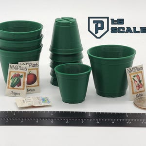 May include: A collection of miniature green plastic plant pots, seed packets, and a ruler. The seed packets are labeled with the names of vegetables. The image also includes the text "1:6 SCALE".
