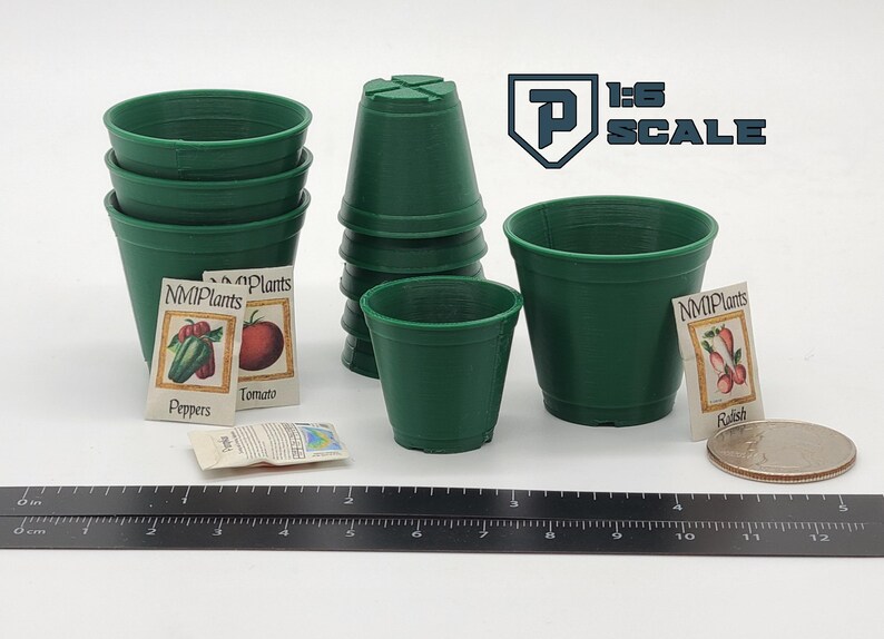 May include: A collection of miniature green plastic plant pots, seed packets, and a ruler. The seed packets are labeled with the names of vegetables. The image also includes the text "1:6 SCALE".