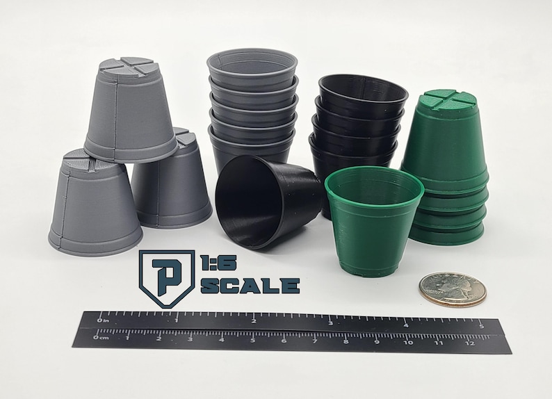May include: A collection of small, plastic plant pots in various colors: gray, black, and green. The pots are arranged on a white surface with a ruler, a coin, and the text "1:6 SCALE".