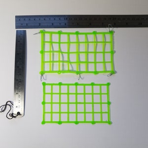 以下が含まれることがあります： 金属製のフックが付いた緑色のプラスチック製のグリッドパネルが2つ。大きなパネルは少し曲がっています。小さなパネルは平らです。