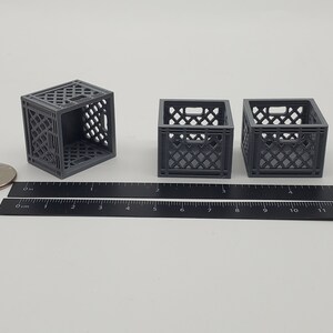 Puede incluir: Tres cajas de leche de pl&aacute;stico gris, cada una mide aproximadamente 5 cm de alto, est&aacute;n dispuestas sobre una superficie blanca. Una regla se coloca debajo de las cajas para la escala.