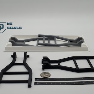 May include: A set of three black and grey metal ladder frames for a 1:6 scale model. The frames are made of plastic and are designed to be used with a model truck or other vehicle. The frames are shown on a white surface with a ruler for scale.