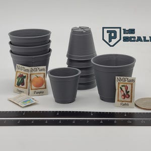 May include: A collection of gray miniature plant pots, seed packets, and a coin. The seed packets are labeled with images of peppers, a pumpkin, and radishes. A ruler is placed at the bottom of the image. The text "1:6 SCALE" is visible.
