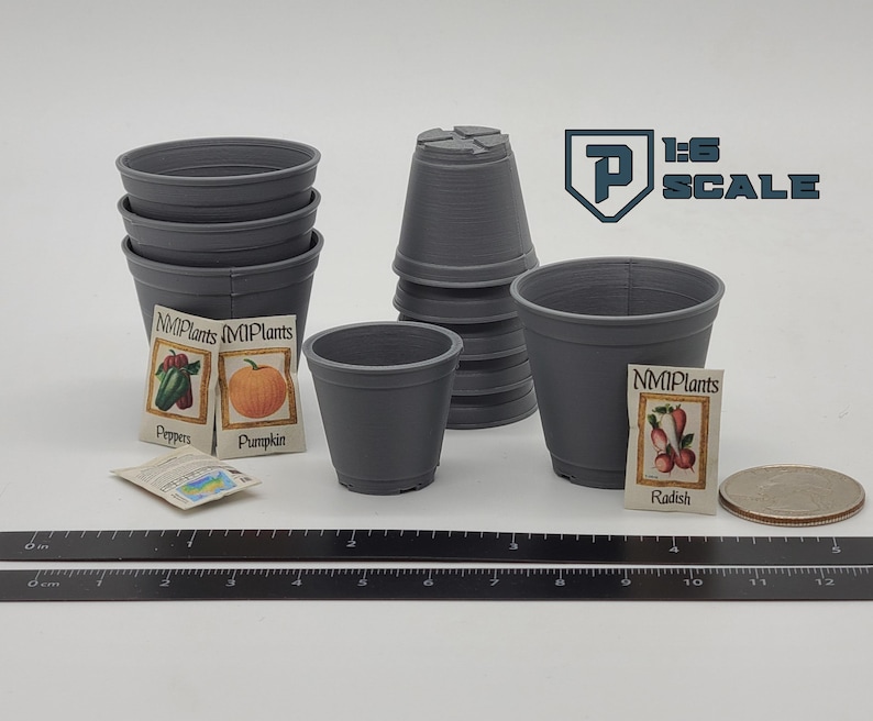 May include: A collection of gray miniature plant pots, seed packets, and a coin. The seed packets are labeled with images of peppers, a pumpkin, and radishes. A ruler is placed at the bottom of the image. The text "1:6 SCALE" is visible.