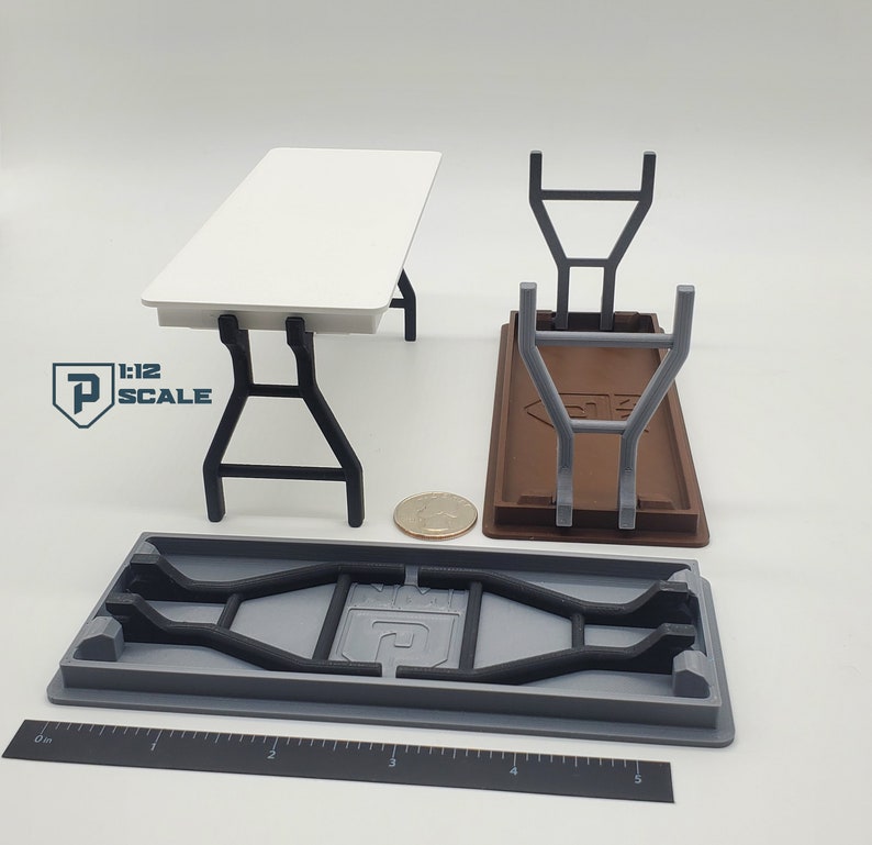 K&ouml;nnte beinhalten: Ein wei&szlig;er Klapptisch mit schwarzen Metallbeinen. Der Tisch ist im Ma&szlig;stab 1:12 und wird zusammengeklappt gezeigt. Der Tisch ist aus Kunststoff und f&uuml;r die Verwendung mit Miniaturfiguren konzipiert.