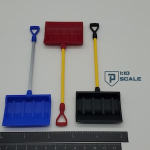 May include: Three miniature snow shovels with different colored handles and blades. The shovels are red, blue, and black. The shovels are 1:10 scale.