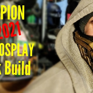 Könnte beinhalten: Eine Person trägt ein Kapuzenpullover und eine goldene und schwarze Maske mit dem Text "SCORPION MK 2021 DIY COSPLAY Mask Build".