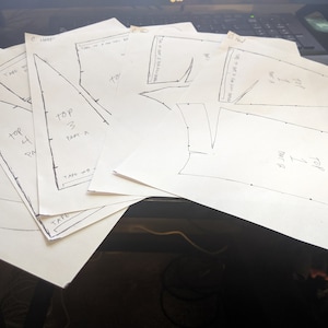May include: A set of paper patterns for sewing a project. The patterns are labeled with numbers and the words "top" and "part".