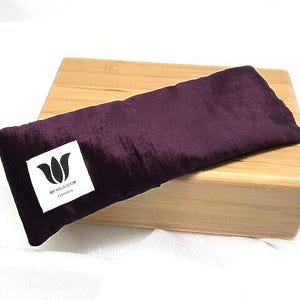 May include: A purple velvet eye pillow with a white label that says "My Yoga Room" on a wooden block.