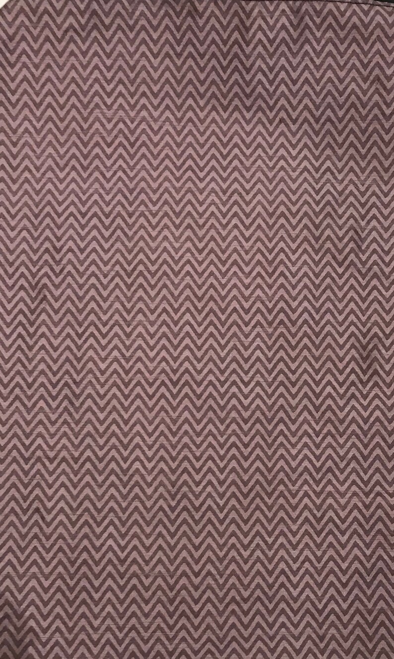 May include: A close-up of a fabric with a chevron pattern in shades of brown and gray.