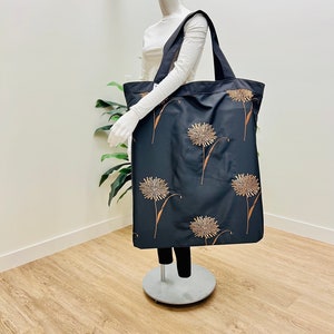 May include: A large black tote bag with a brown dandelion print. The bag has two long handles.