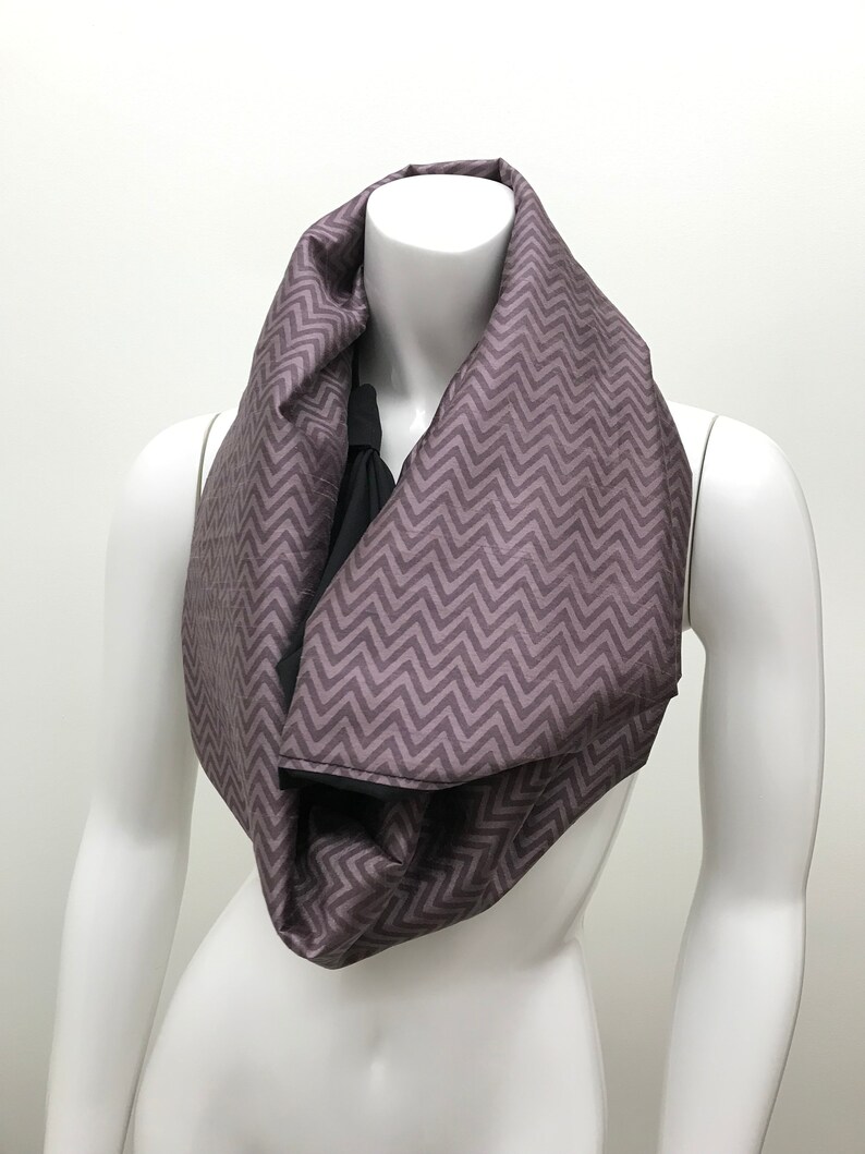 May include: A purple and black infinity scarf with a chevron pattern.