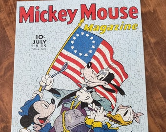 May include: A vintage Mickey Mouse Magazine cover featuring Mickey Mouse, Donald Duck, and Goofy dressed in patriotic attire. The cover features a large American flag with 13 stars and the text "Mickey Mouse Magazine" in red and yellow letters. The date on the cover is "July 1939, Vol. 4, No. 10".