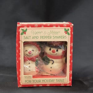 May include: A white ceramic mug with a black handle and the text "But First, Coffee" in a black, handwritten-style font. The mug is on a white surface.