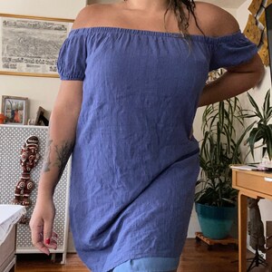 May include: A blue off-the-shoulder dress with short sleeves. The dress is made of a soft, lightweight fabric and has a relaxed fit.