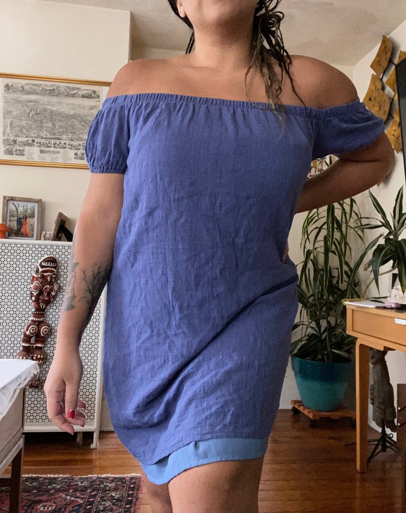 May include: A blue off-the-shoulder dress with short sleeves. The dress is made of a soft, lightweight fabric and has a relaxed fit.