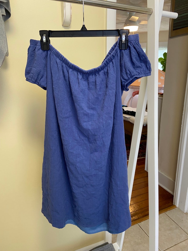 May include: A blue off-the-shoulder dress with short sleeves. The dress is made of a soft, textured fabric.