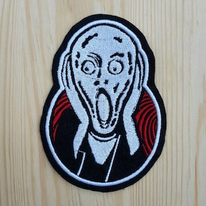 Peut inclure: Patch brodé noir et blanc représentant le tableau iconique "Le Cri" d'Edvard Munch. Le patch présente un visage blanc avec une bouche grande ouverte, de grands yeux et des mains qui se couvrent les oreilles. L'arrière-plan est noir avec des lignes rouges tourbillonnantes.