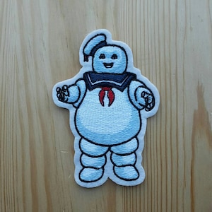 Peut inclure: Patch thermocollant brodé représentant un fantôme bleu et blanc avec un nœud papillon rouge. Le fantôme sourit et porte un col de marin.