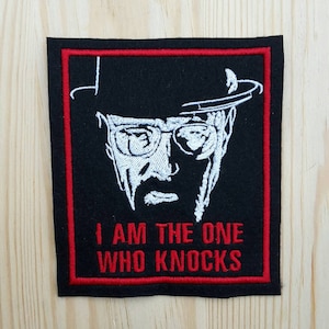 Könnte beinhalten: Schwarz-weiß gestickter Aufnäher mit einem Porträt eines Mannes mit Hut und Brille. Der Text "I am the one who knocks" befindet sich unter dem Porträt.