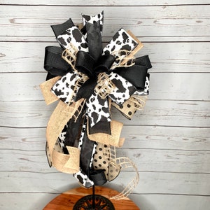 Black and White Cow Bow on a wreath stand with a distressed wood photography background.  The wreath stand is for display only and not for sale. Refer to the listing description for further bow details.