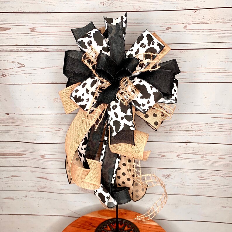 Black and White Cow Bow on a wreath stand with a distressed wood photography background.  The wreath stand is for display only and not for sale. Refer to the listing description for further bow details.