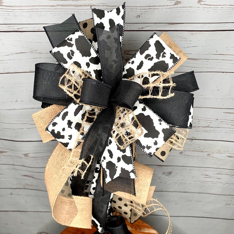 Black and White Cow Bow on a wreath stand with a distressed wood photography background.  The wreath stand is for display only and not for sale. Refer to the listing description for further bow details.