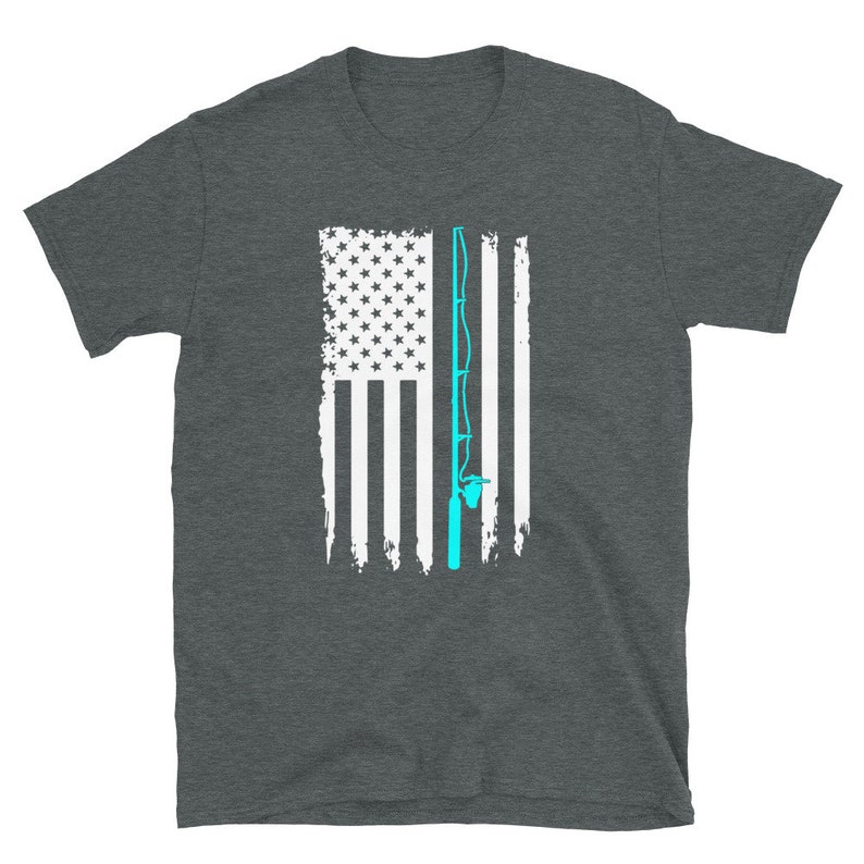 May include: Dark gray t-shirt featuring a distressed American flag design with a light blue fishing rod overlay. The flag has white stripes and a field of white stars. The shirt is made of a soft material.
