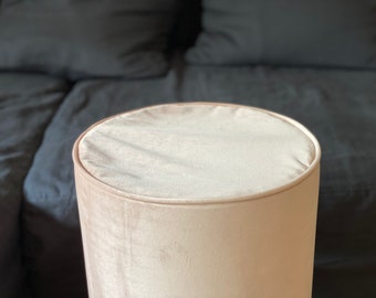 May include: A light beige round ottoman with a soft, plush velvet fabric covering.