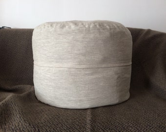 May include: A round, light gray linen ottoman with a seam around the middle.