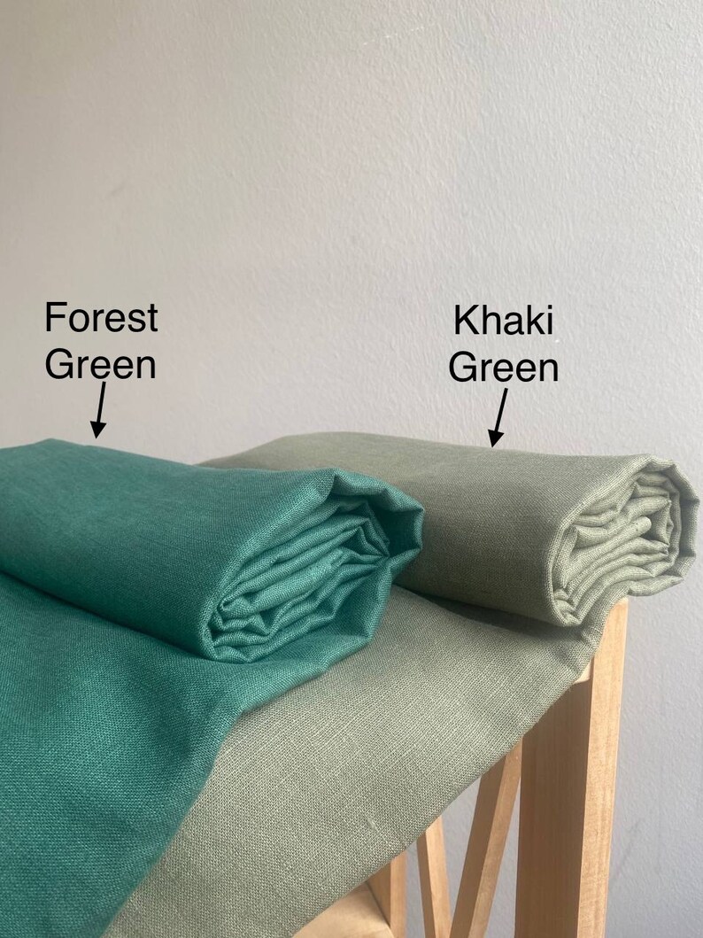 May include: Two fabric swatches, one forest green and one khaki green, rolled up and displayed on a wooden surface.