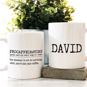 May include: Two white ceramic mugs. One mug has the word "PROCAFFEINATING" with a definition and the other mug has the name "DAVID" printed on it.
