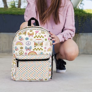 May include: A white backpack with a checkered pattern and colorful retro designs, including a rainbow, butterflies, peace signs, and a vintage van.