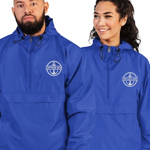 May include: Two blue hooded anorak jackets. One jacket has the text "CAPTAIN BOB" with an anchor design, and the other has "FIRST MATE JENNY" with an anchor design. Both jackets have a front pocket and a zipper.