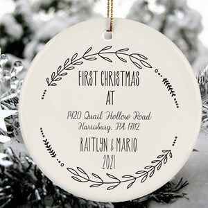 May include: White ceramic Christmas ornament with black text that reads "First Christmas at 1420 Quail Hollow Road Harrisburg, PA 17112 Kaitlyn & Mario 2021". The ornament is decorated with a black wreath design.