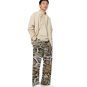 Peut inclure: Une personne portant une chemise boutonnée beige et un pantalon à imprimé serpent brun et noir.