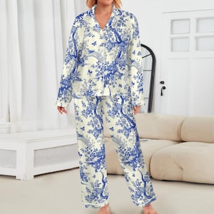 May include: Cream-coloured two-piece pyjama set with a blue floral and bird design. The long-sleeved top has a notched collar and button-down front. The trousers are long and straight-legged. The set is made of a soft, lightweight fabric.