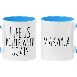 May include: Two white ceramic mugs with blue rims and handles. One mug says "Life is better with goats" and the other mug says "Makayla".